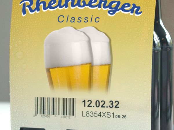 Industrielle Inkjet-Codierung mit MHD und Barcode auf gelber Kartonverpackung